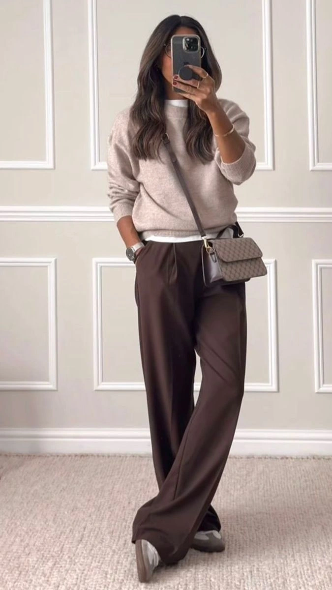 Woman in wide leg chocolate brown trousers with a beige sweater in a mirror selfie
