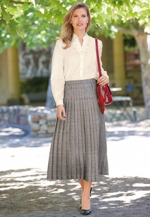 Cream blouse with a grey pleated midi skirt and a red shoulder bag