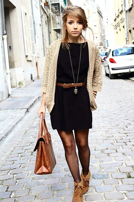 Black midi dress with a long cream cardigan and tan boots on a cobblestone street