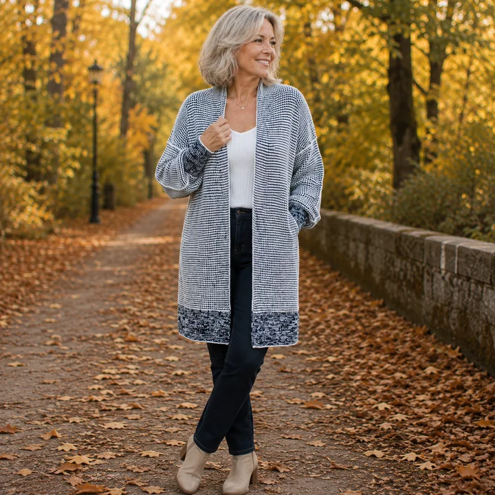 Mature woman in blue long cardigan and dark pants in autumn park