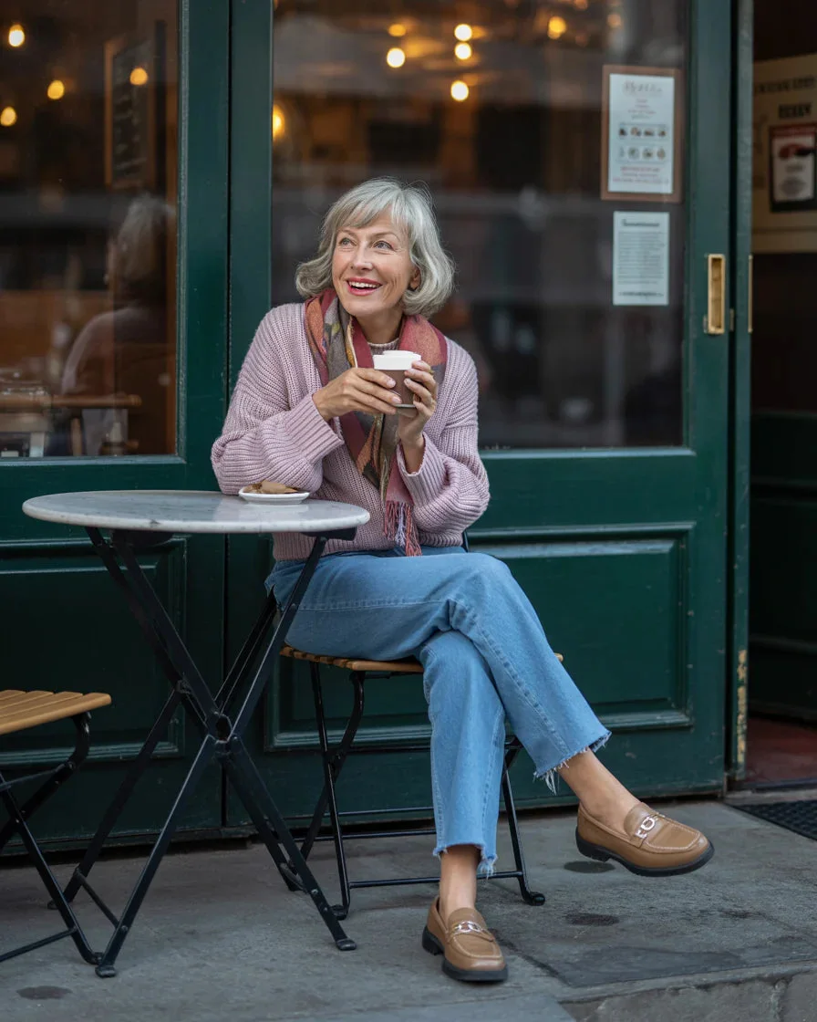 Mature woman in lavender cardigan scarf and jeans at cafe