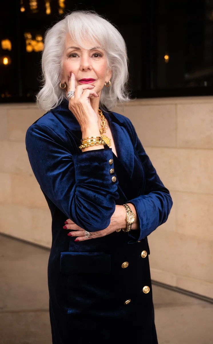 Mature woman in royal blue velvet blazer with gold jewelry