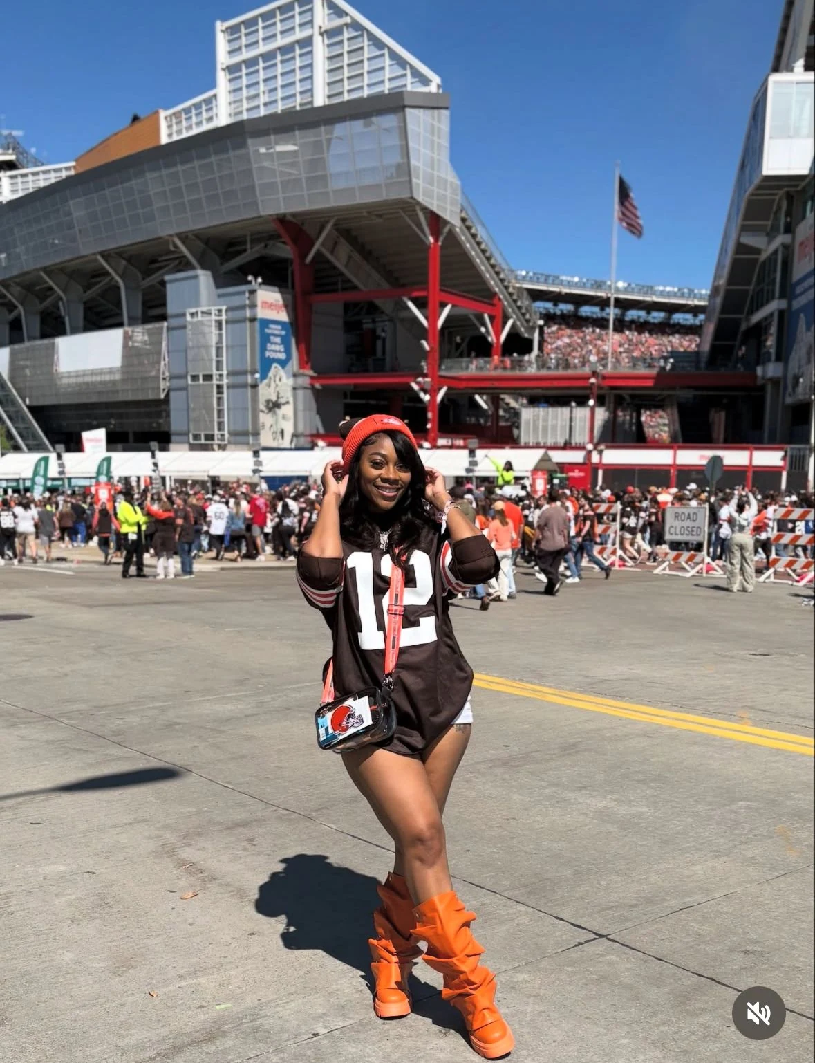 Fall game day outfit for Black women: brown number jersey with orange slouch boots and orange beanie at the stadium