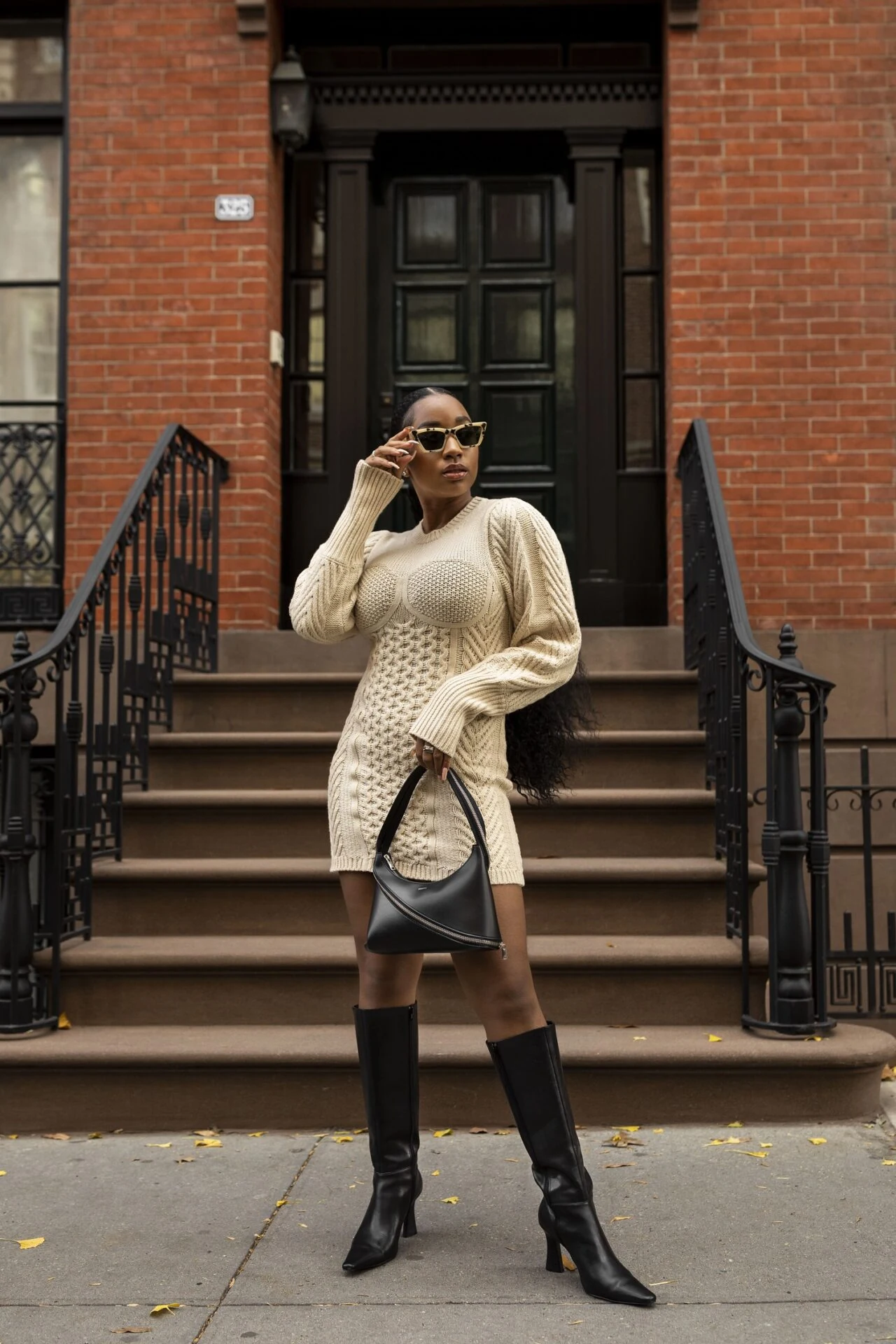 Fall game day outfit for Black women: cream cable-knit sweater dress with black knee-high boots