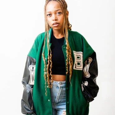 Fall game day outfit for Black women: green varsity jacket with black top and ripped jeans