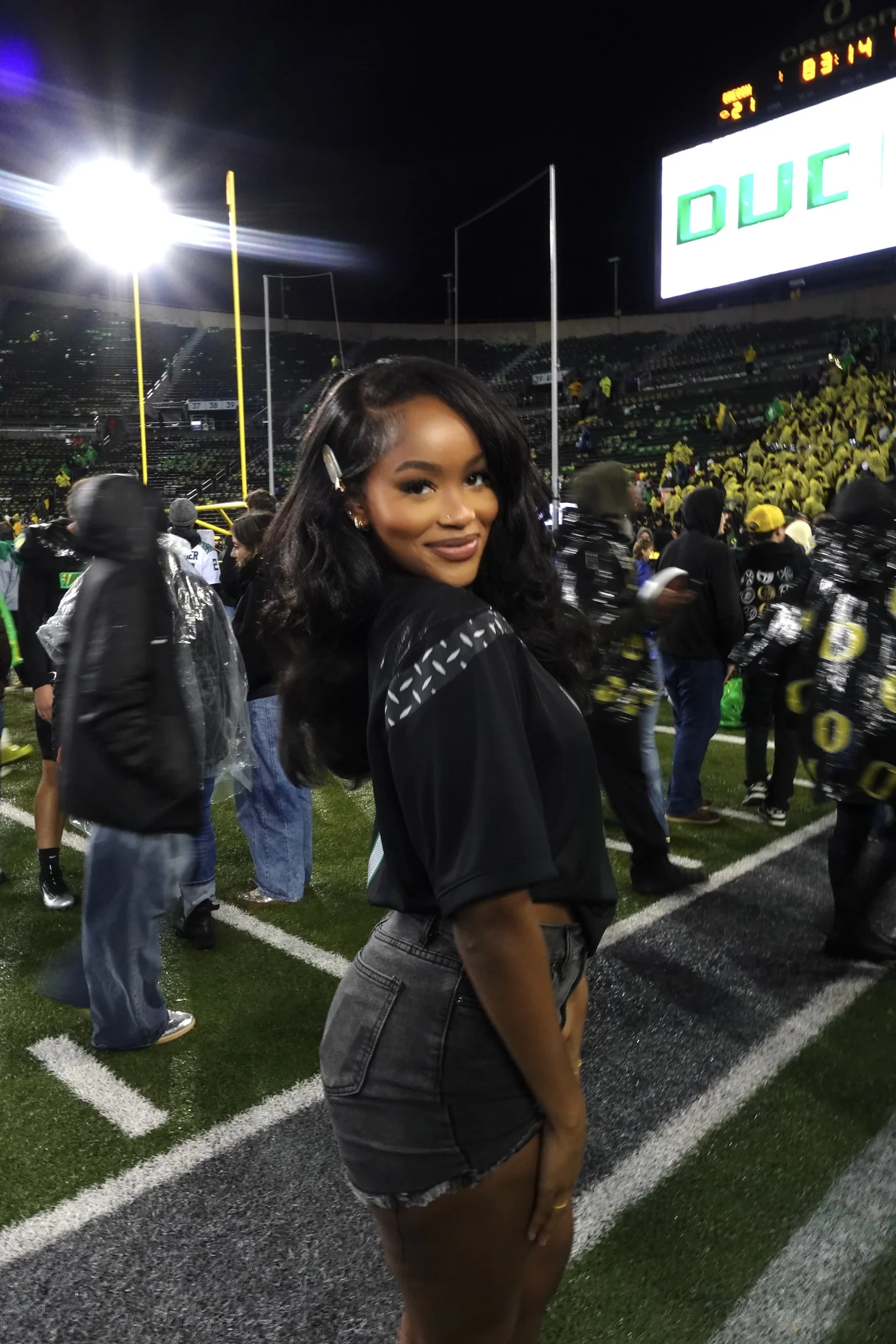 Fall game day outfit for Black women: black jersey with denim skirt at a night football game