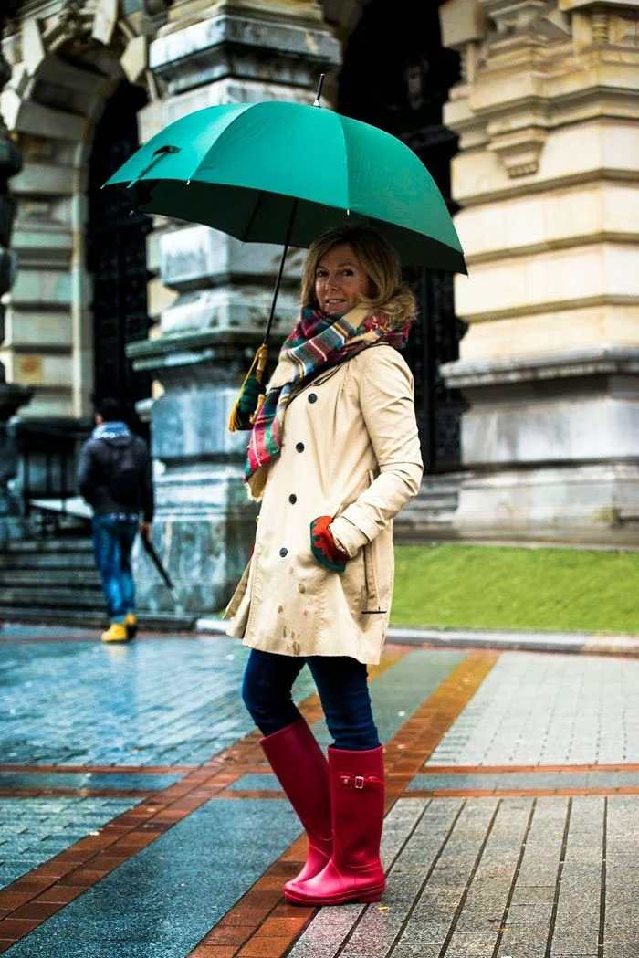 Fall rainy day outfit: beige trench coat with patterned scarf and jeans in the rain
