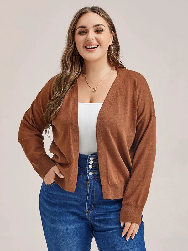 Plus size fall game day outfit: long brown cardigan over white top with dark jeans