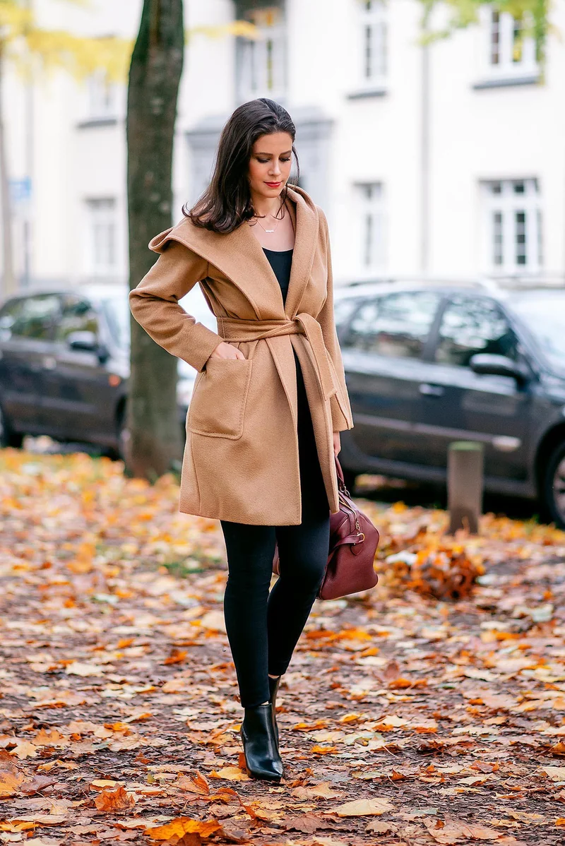 Plus size fall game day outfit: camel coat over black turtleneck and jeans