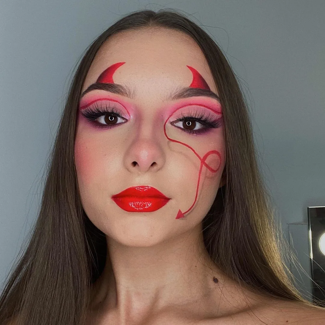Devil girl makeup with red horns and red cheek tail