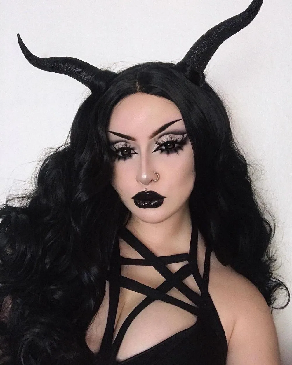 Horned devil makeup with black horns and winged liner