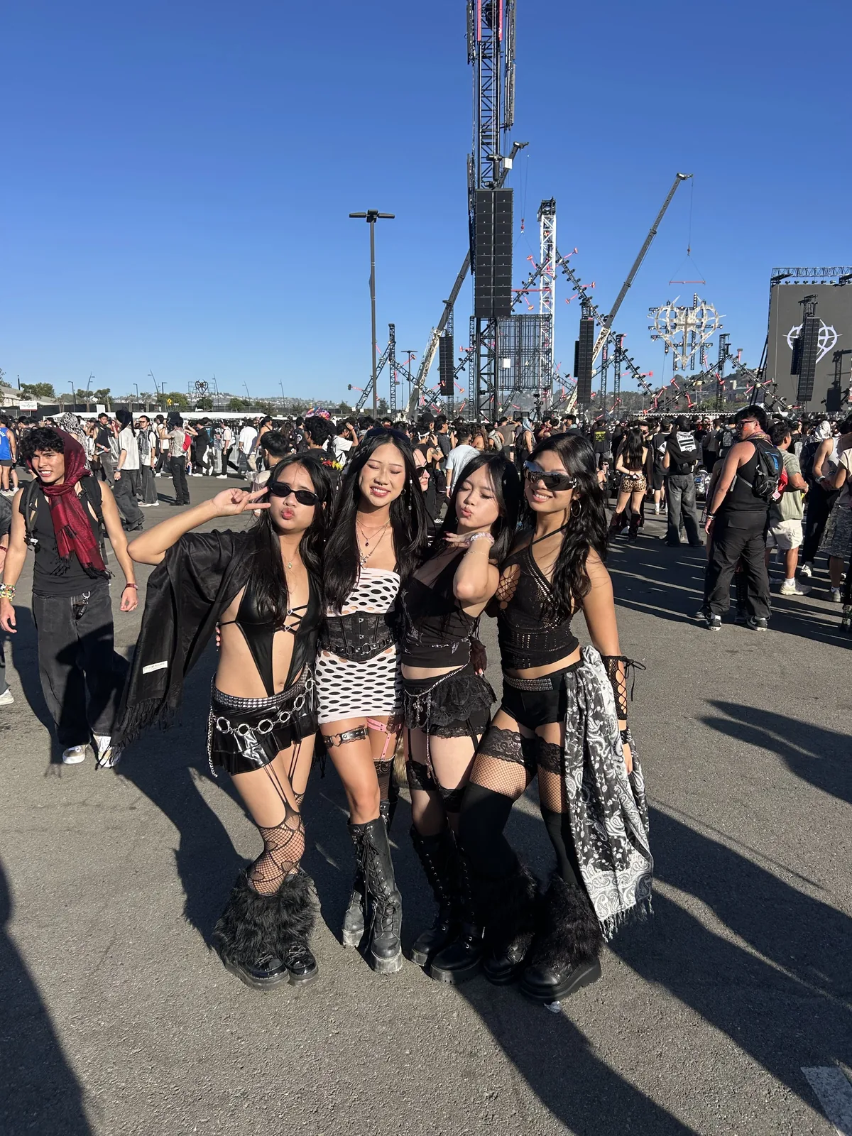 III points festival outfit: group of women in black festival outfits at outdoor festival grounds