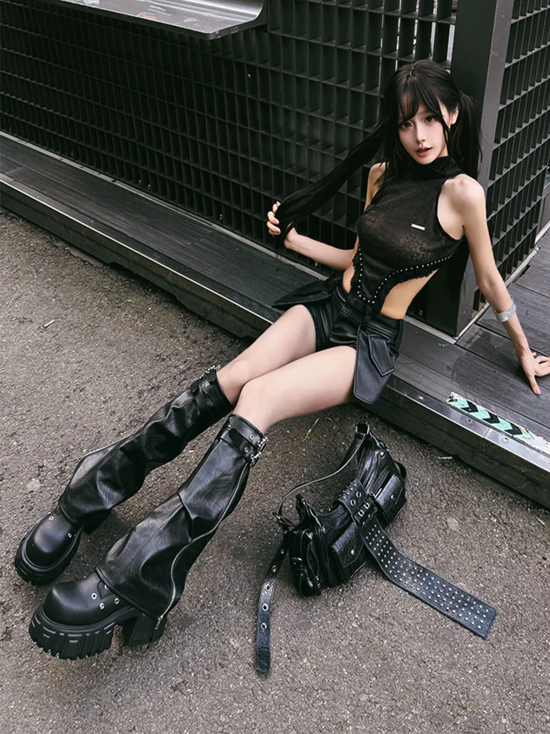 III points festival outfit: black mesh top with a mini skirt and platform boots by a city fence