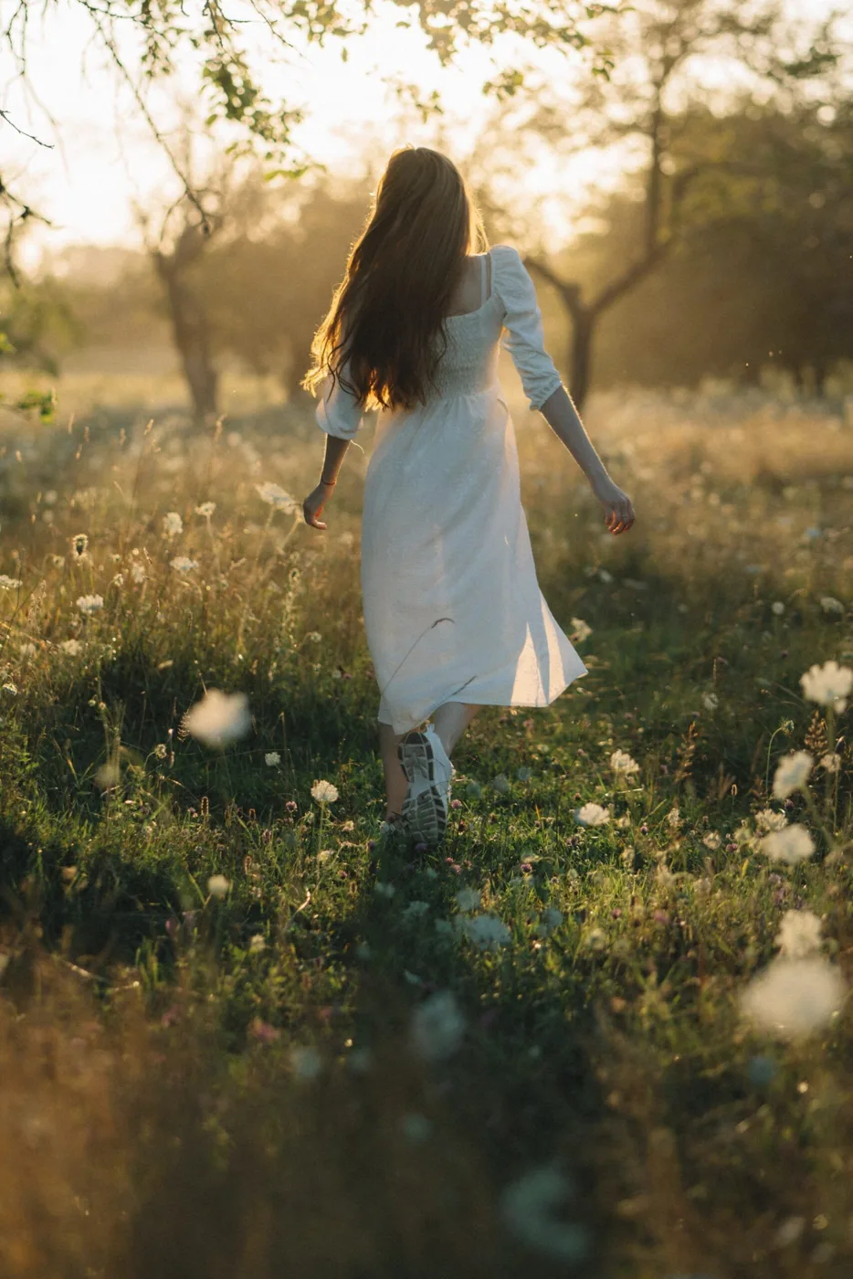 White midi dress walking through sunlit meadow