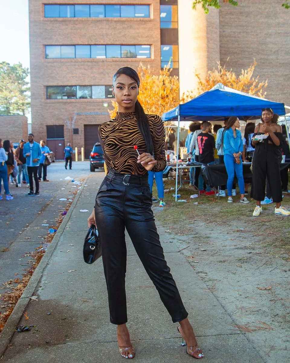 Black woman in a zebra print top and black trousers at a homecoming tailgate street