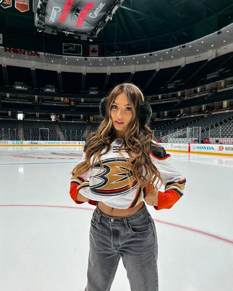 Woman in an Anaheim Ducks hockey jersey and jeans standing on the ice