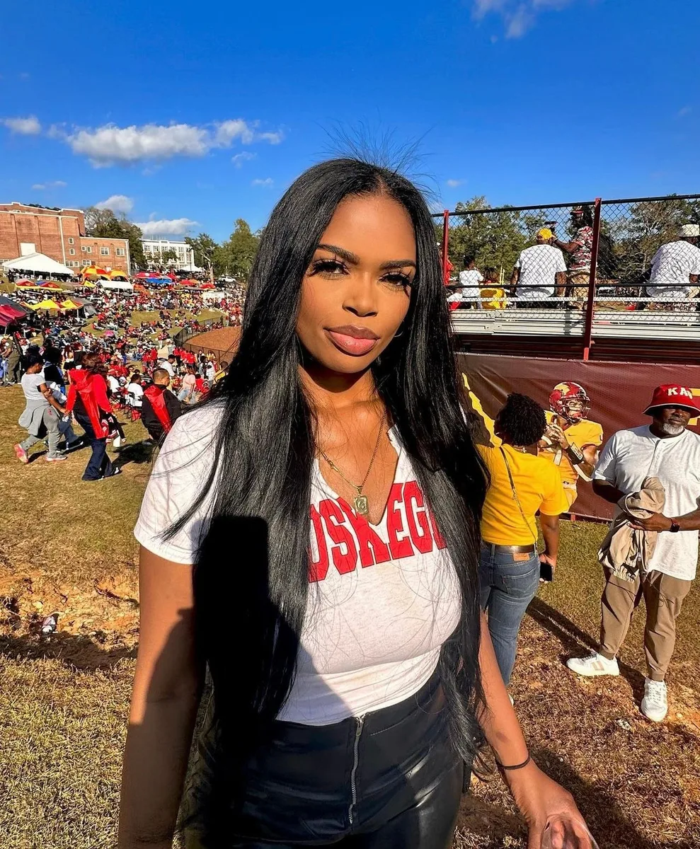 Black woman in a white graphic tee and black leather skirt at a tailgate