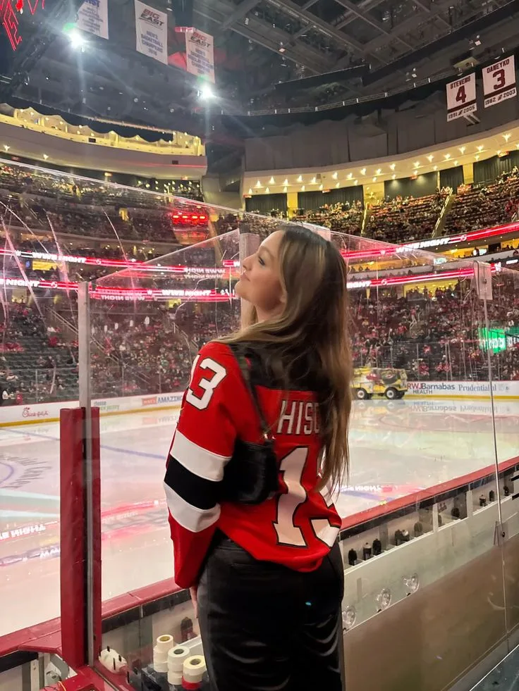 Woman in a red number 3 hockey jersey on the ice at an arena