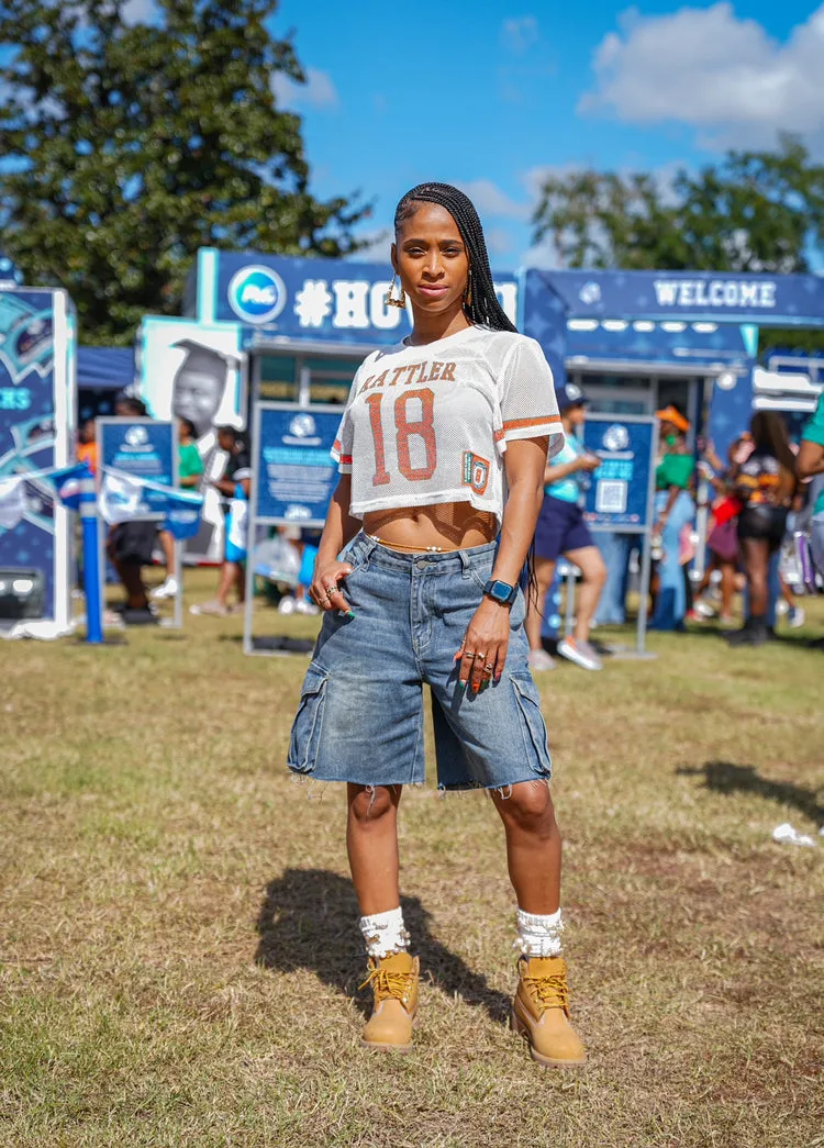 Black woman in a cropped football jersey and denim shorts with timberland boots at homecoming