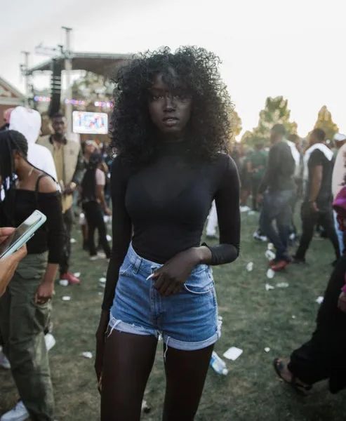Black woman in a black long sleeve top and denim shorts at a homecoming event
