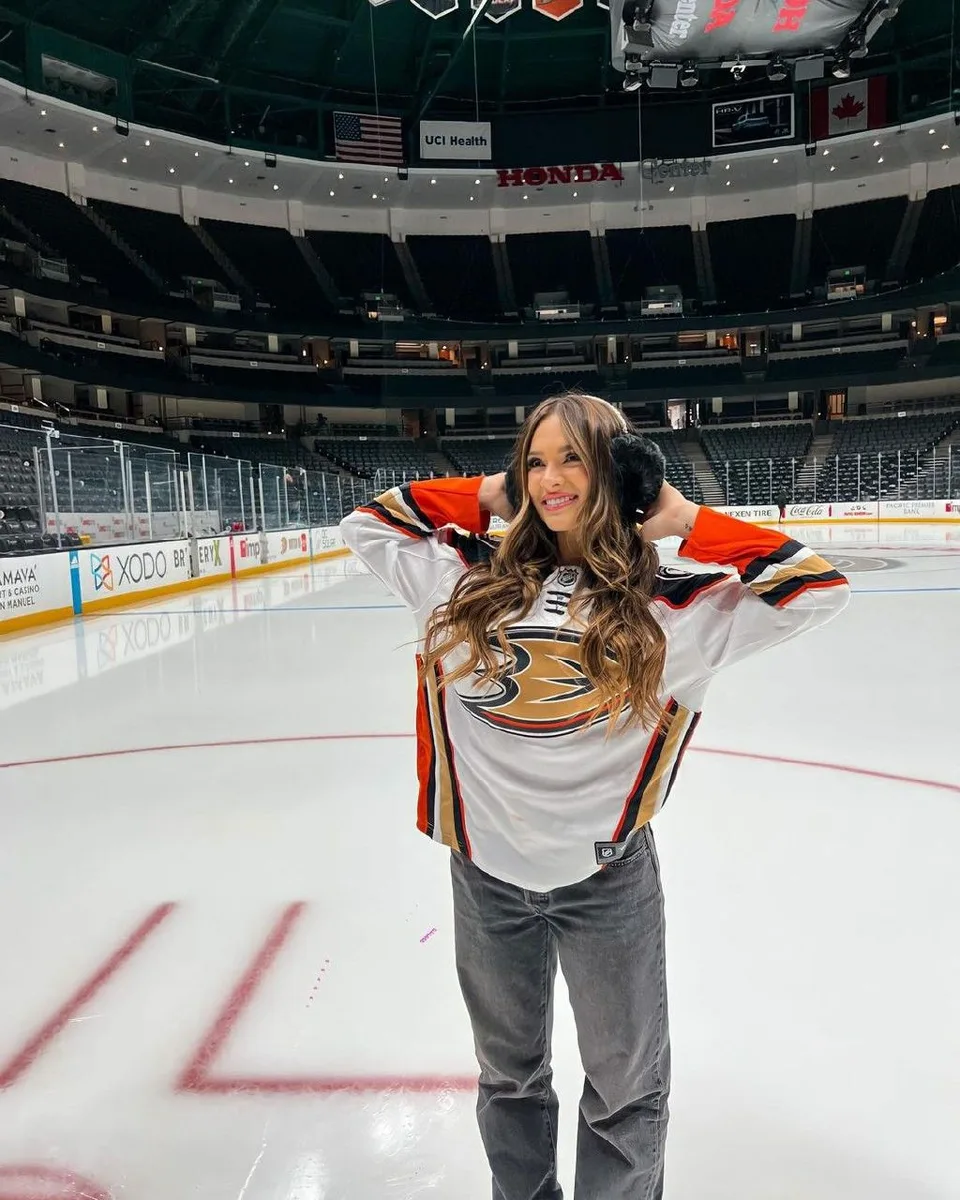 Woman in a Ducks hockey jersey and jeans on the ice