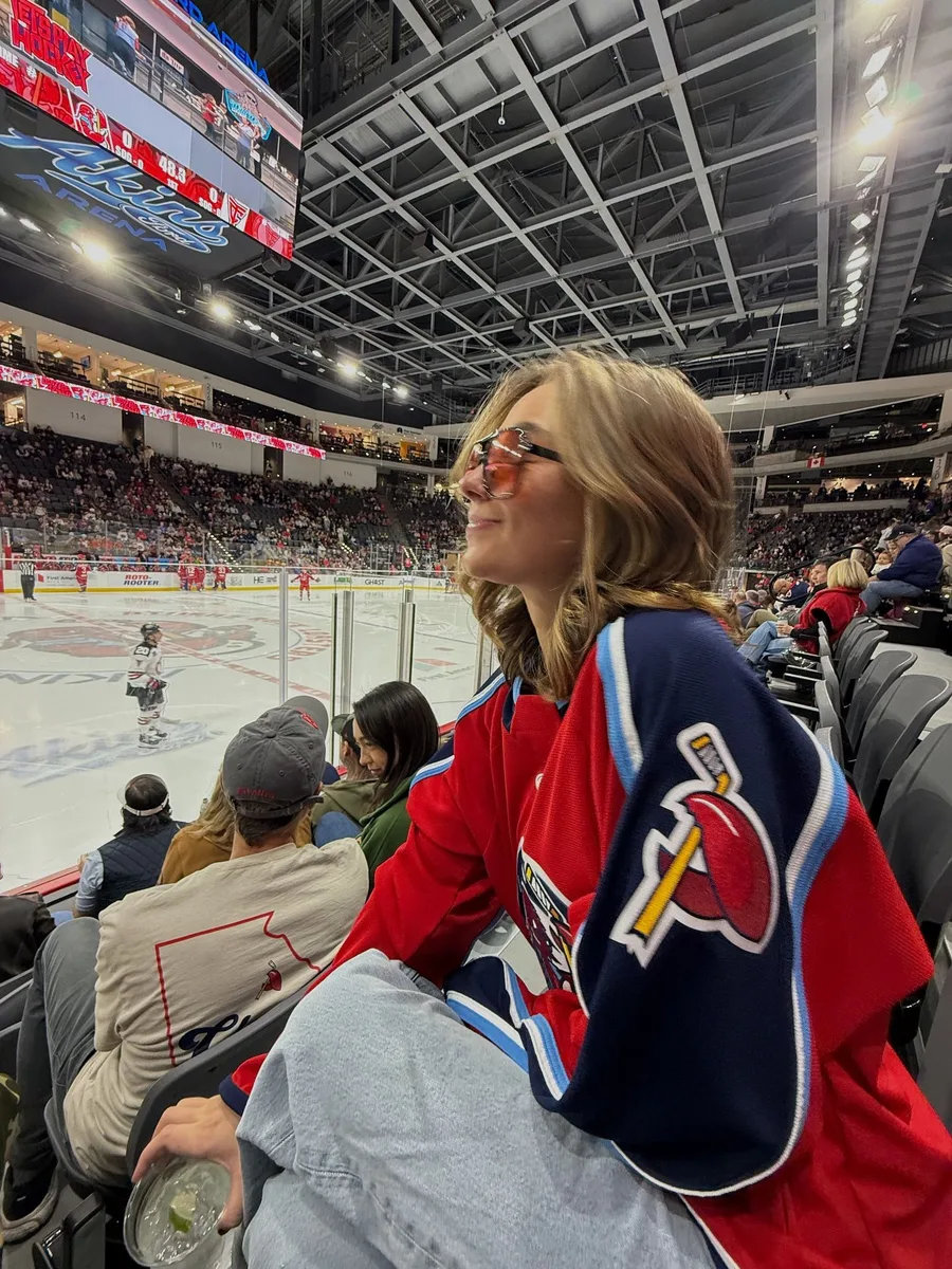 Woman in a red hockey jersey sitting in arena seats
