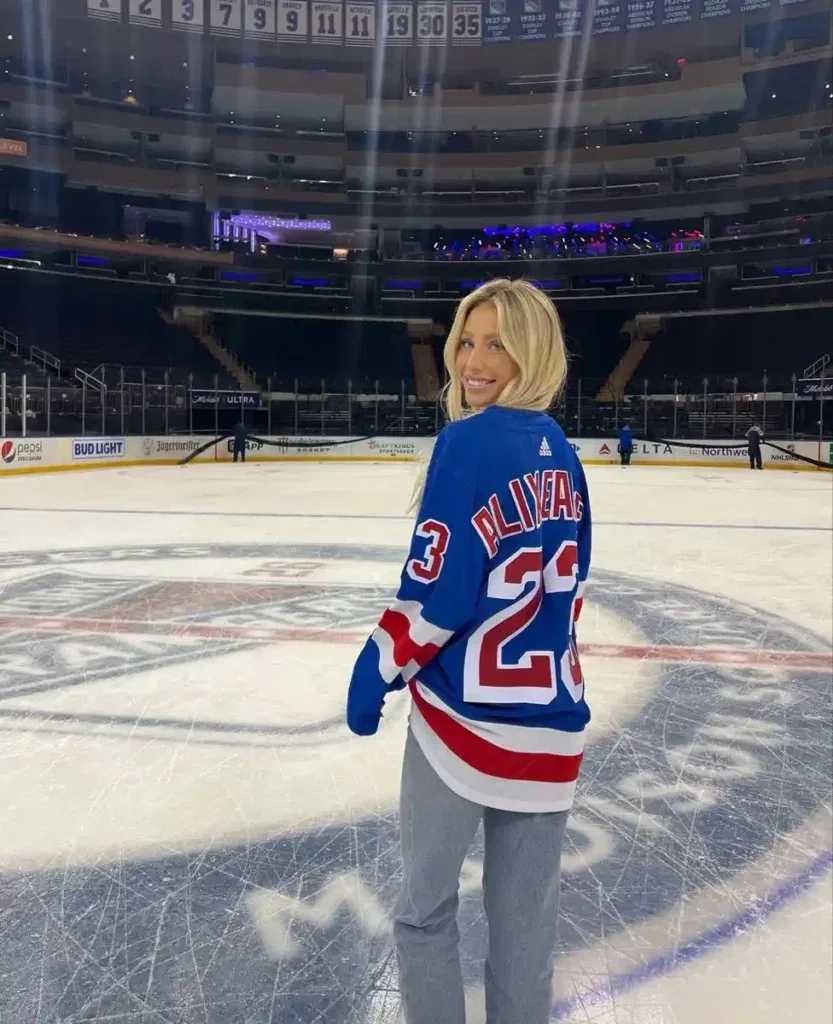 Woman in a blue Rangers number 23 jersey standing on the ice