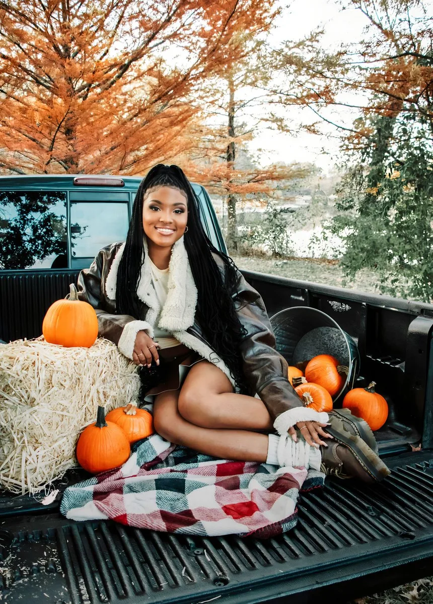 Black woman sitting with pumpkins at a fall homecoming tailgate