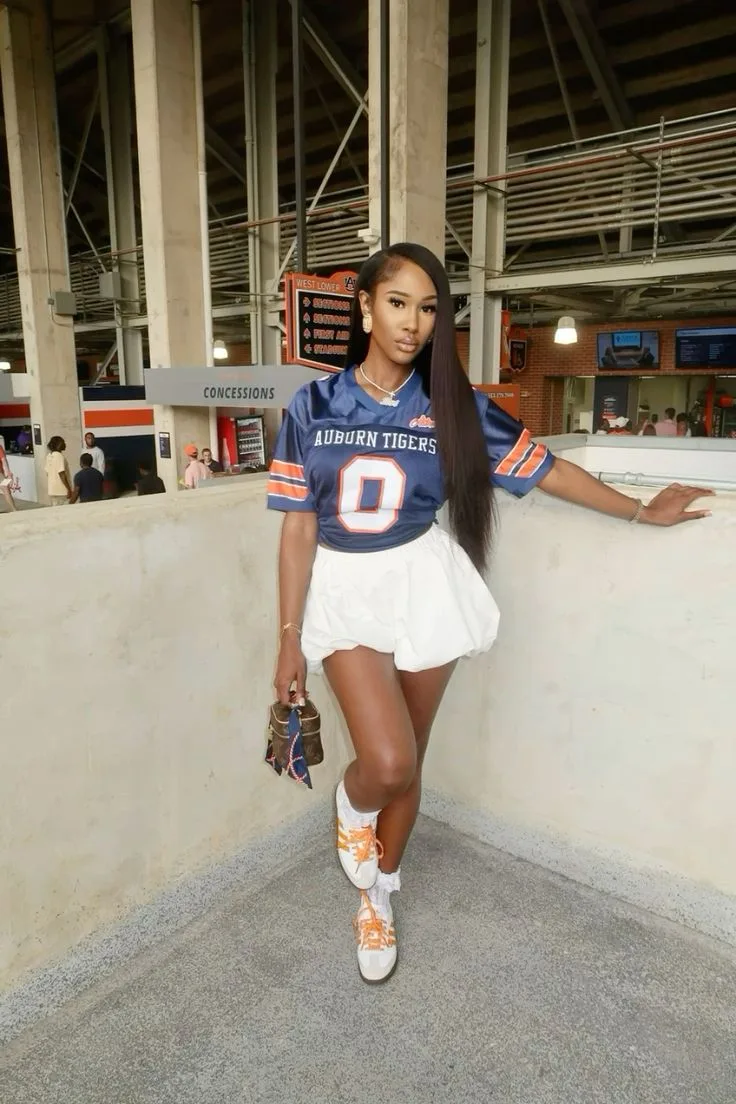 Black woman in a navy football jersey and white skirt at homecoming