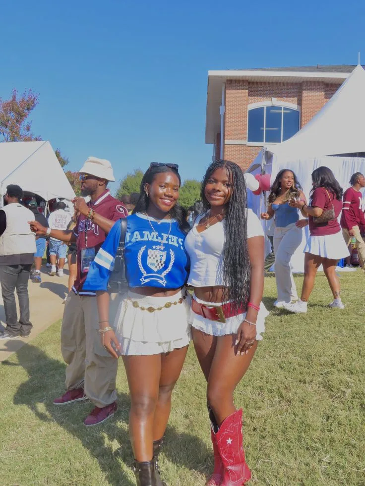 Two Black women in blue jerseys and white skirts with red cowboy boots at a tailgate