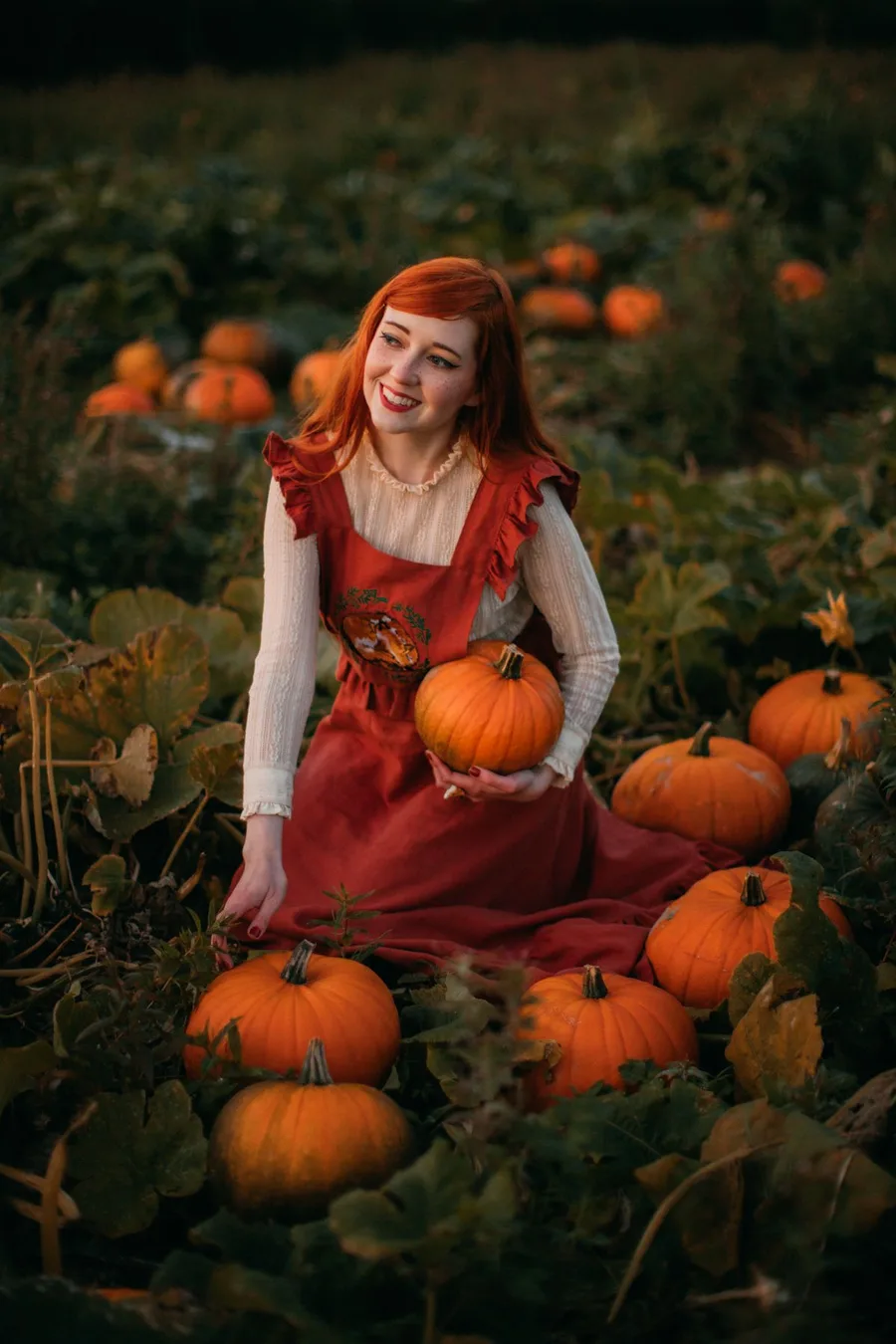 Cute fall pumpkin patch outfit: red fit and flare dress holding a pumpkin