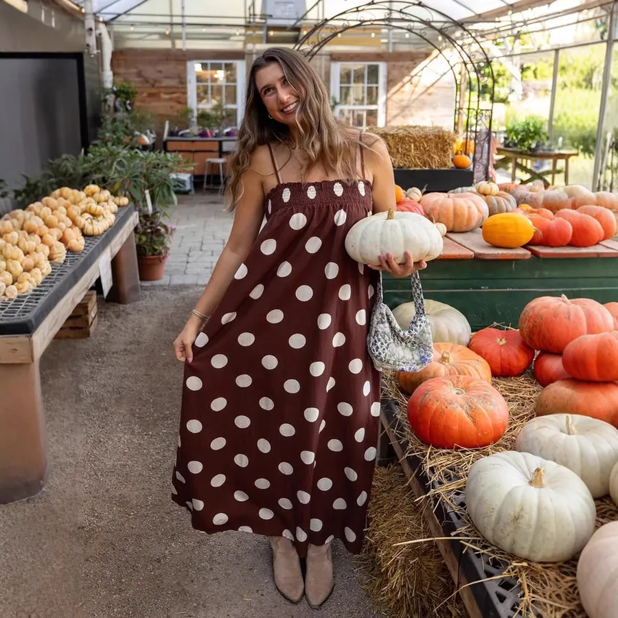 Pumpkin stand outfit: brown polka dot midi dress holding a white pumpkin