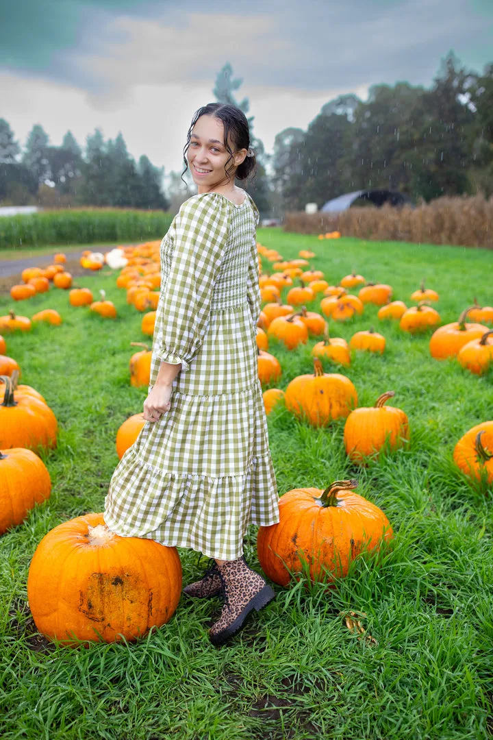 Cute pumpkin patch dress: green gingham midi dress standing among pumpkins