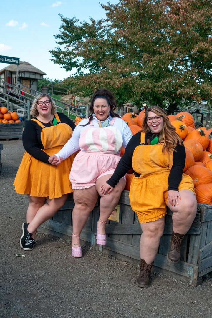 Plus size pumpkin patch outfits: three women in yellow dresses sitting on a wagon