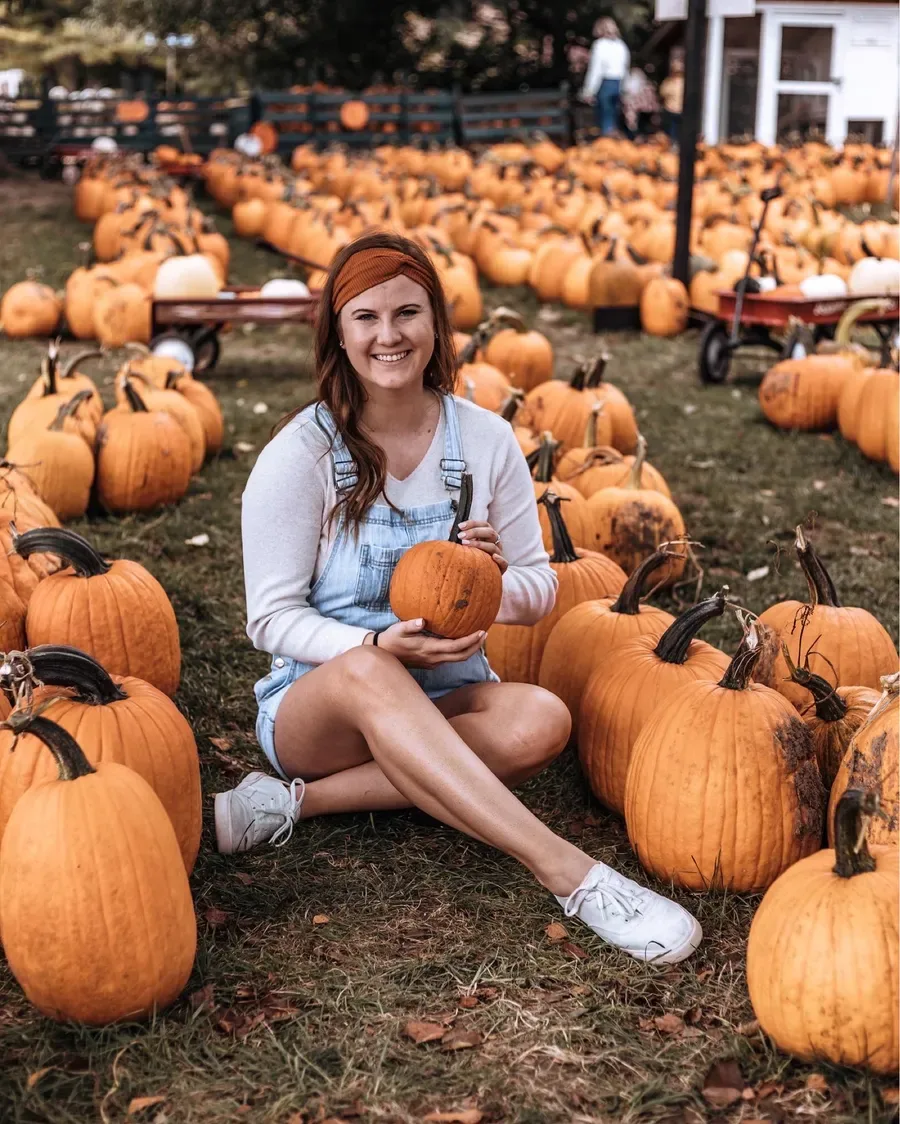 Pumpkin patch outfit: light denim dress sitting among pumpkins
