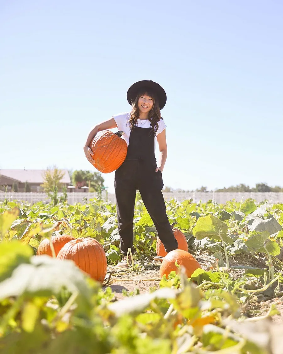Pumpkin patch outfit: black overalls with a white top holding a pumpkin