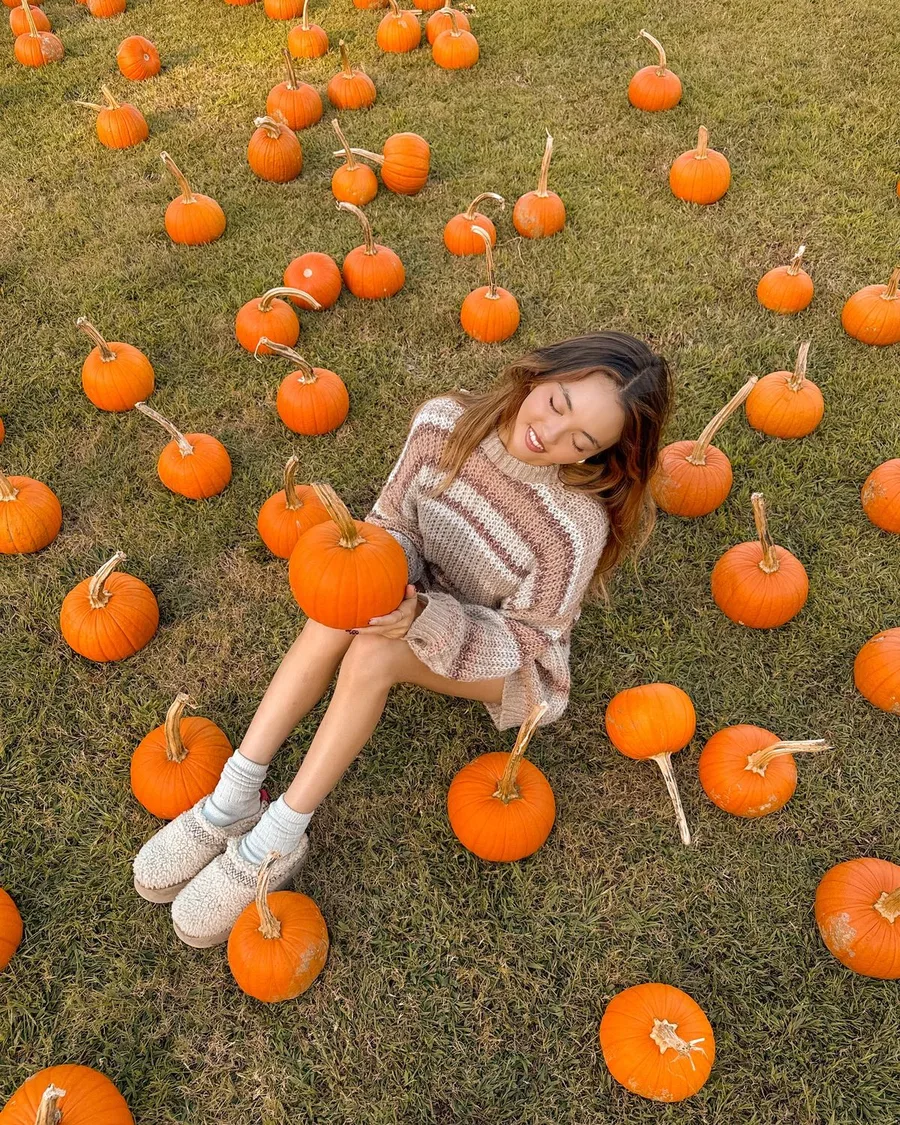 Pumpkin patch outfit: striped sweater lying among mini pumpkins