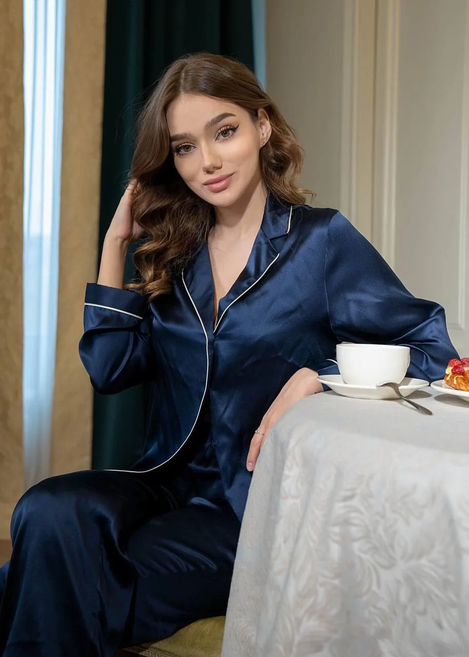 Woman in navy silk pajamas having coffee at a table