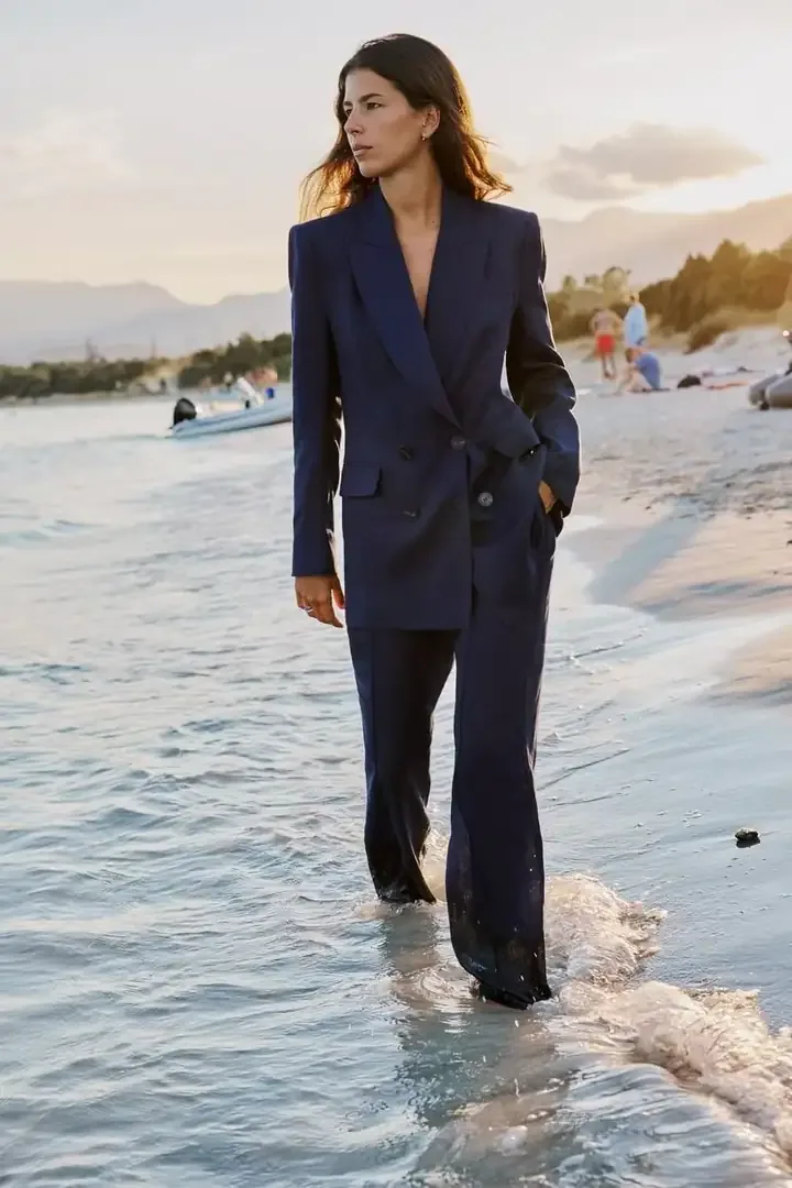 Woman in a navy suit walking in the ocean surf