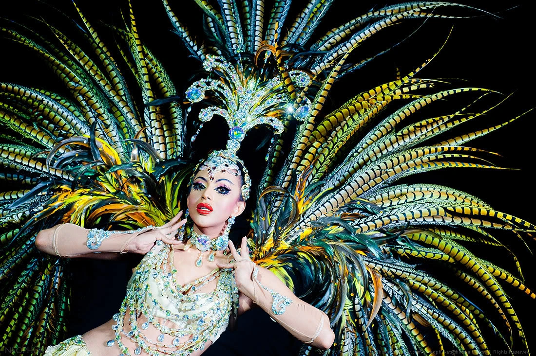 Showgirl in peacock feather costume with large feather fans