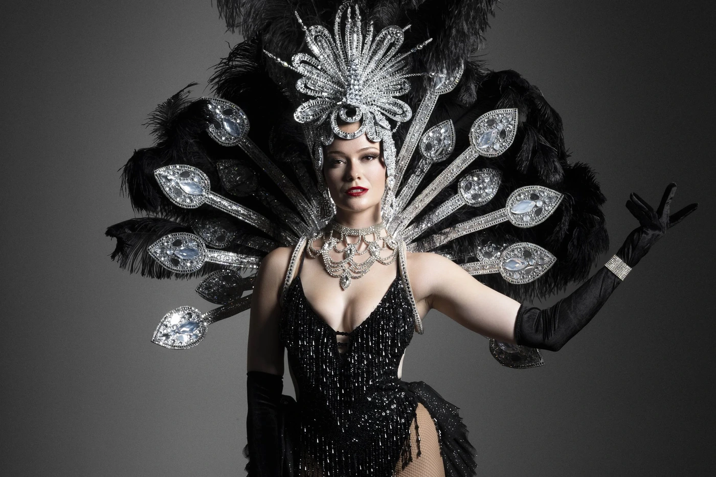 Showgirl in black sequin costume with jeweled peacock headpiece