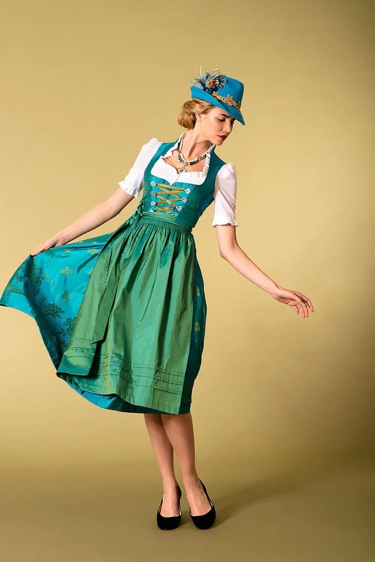 Woman twirling in an emerald green dirndl with a matching alpine hat