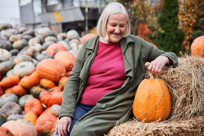Pumpkin patch outfit: green jacket with a pink top sitting on hay