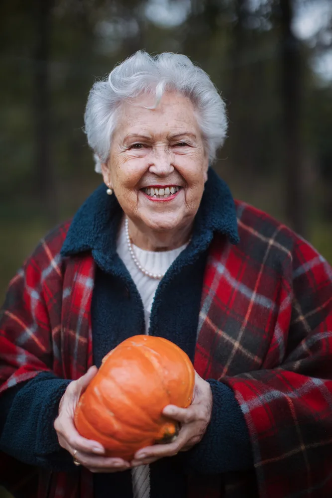 Pumpkin patch outfit for senior women: red plaid shirt holding a pumpkin