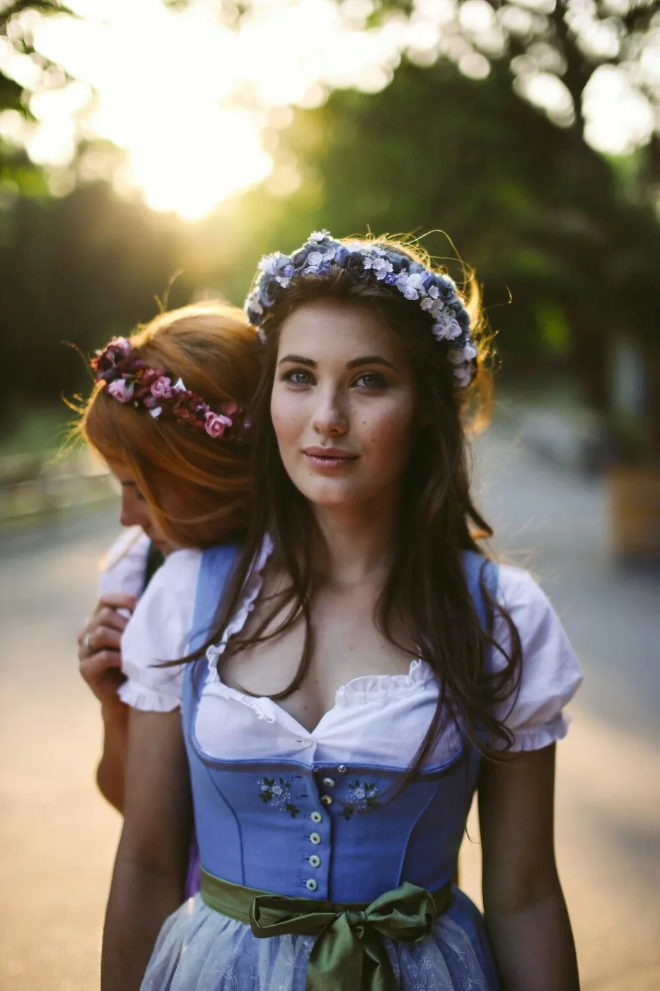 Young woman in a blue dirndl with a flower crown at sunset