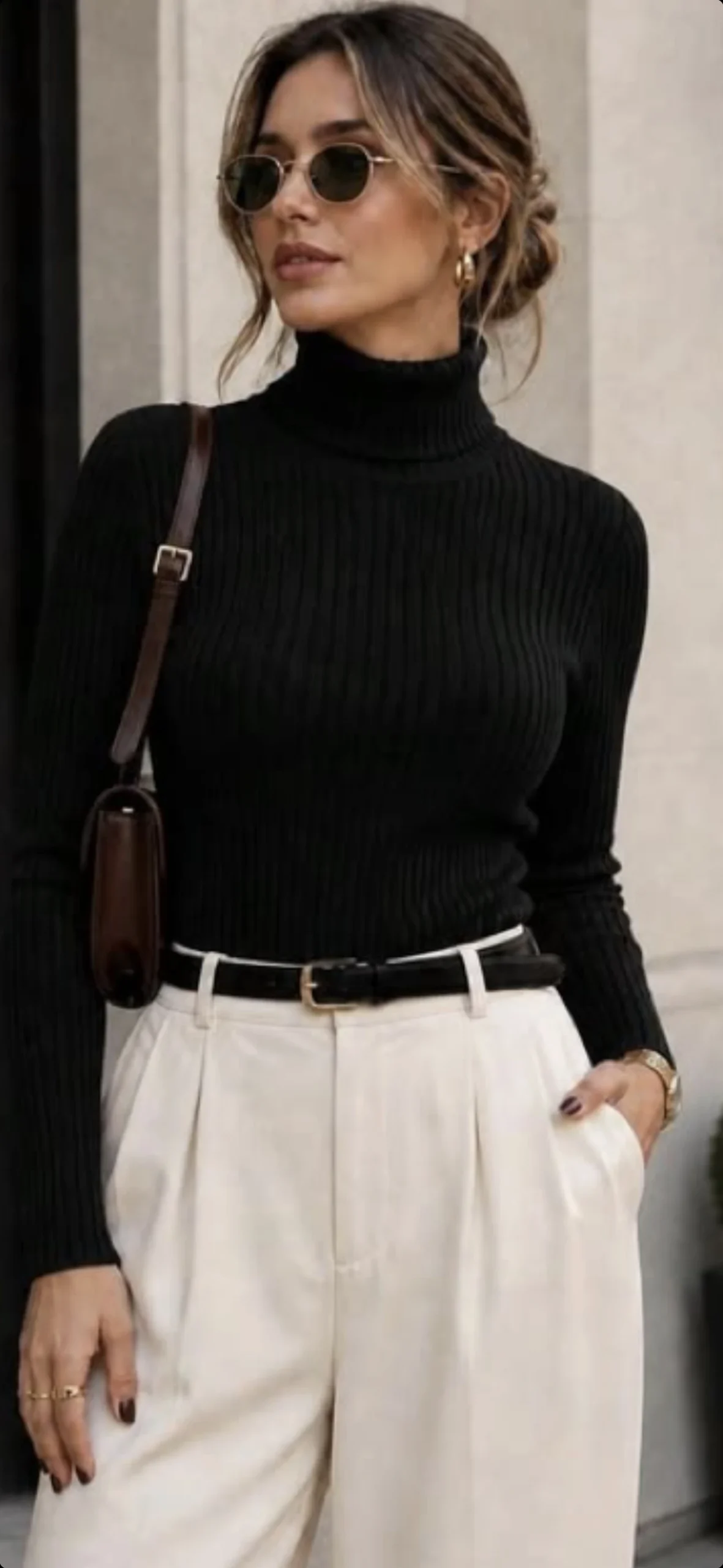 Woman in a black turtleneck and cream wide trousers with a brown bag