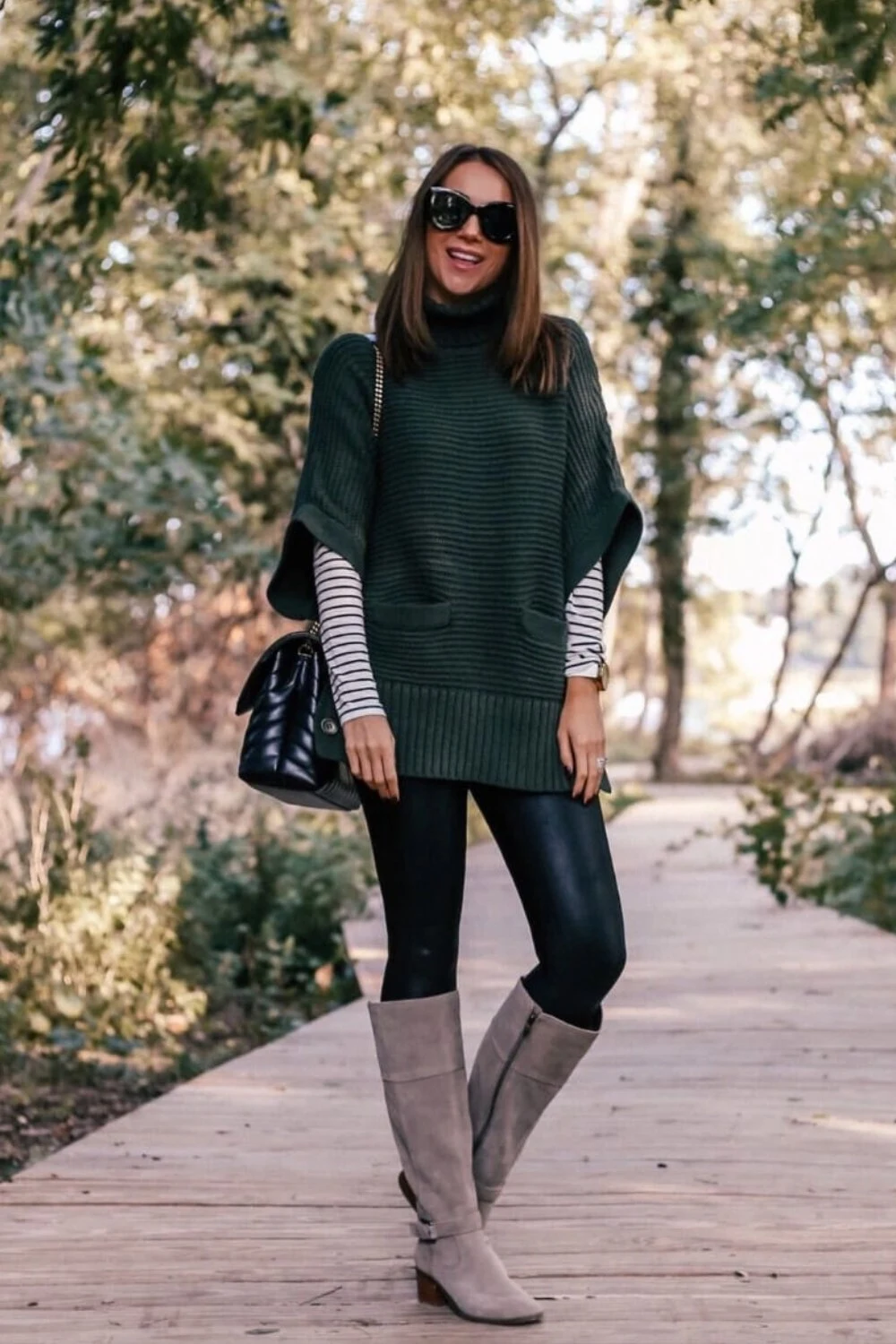 Dark green knit poncho with black leggings and boots