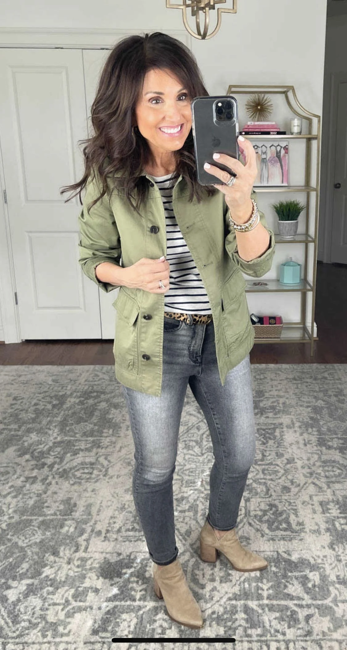 Woman wearing grey jeans with brown boots and an olive jacket in fall