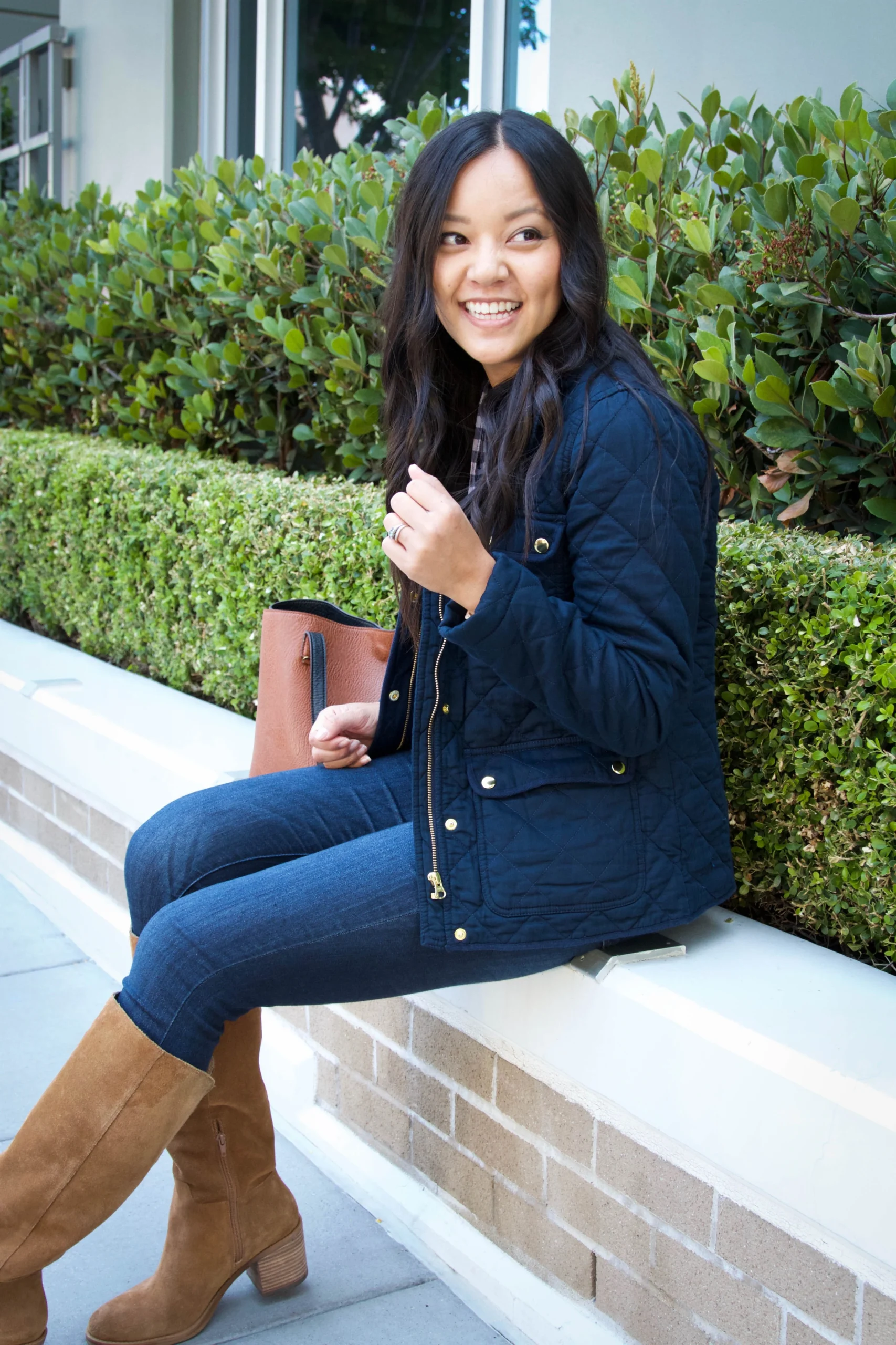 Woman wearing skinny jeans with riding boots and a quilted jacket in fall
