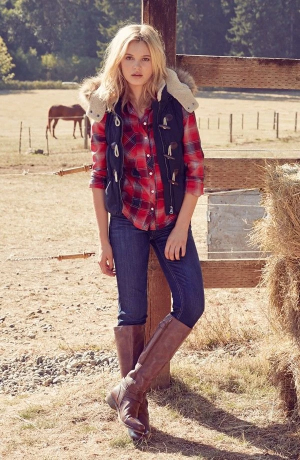 Woman wearing jeans with cowboy boots, a plaid shirt, and a vest in fall